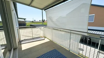 Sonniger Balkon mit Sichtschutz und weitem Blick auf die umliegende Landschaft.