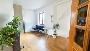 Heller Büroraum mit Holzfußboden, Wartebereich und Pflanzen, ideal für Empfang oder Besprechungen.