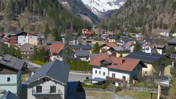 Weitläufiger Blick über das Tal mit Siedlung und majestätischen Bergen im Hintergrund.