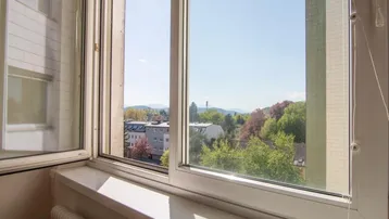 Weitblick aus dem Fenster über die Stadt und die umliegende Landschaft mit Bergen.