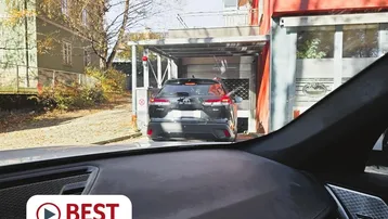 Einfahrt zu einer überdachten Parkmöglichkeit mit einem Fahrzeug im Vordergrund.