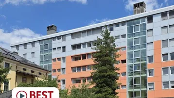 Modernes Mehrfamilienhaus mit farbiger Fassade und großen Glasflächen unter blauem Himmel.