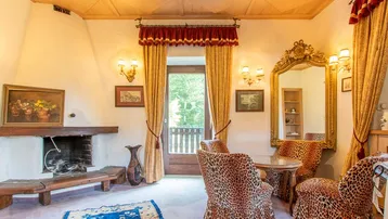 Gemütliches Wohnzimmer mit Kamin, Holzkassettendecke und auffälligen Leopardenmuster-Sesseln.