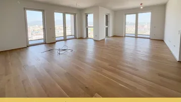 Helles, geräumiges Zimmer mit Holzboden und großen Fenstern, die einen weiten Stadtblick bieten.
