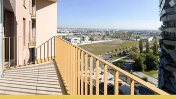 Geräumiger Balkon mit Fliesenboden und weitem Blick über die Stadt und grüne Flächen.