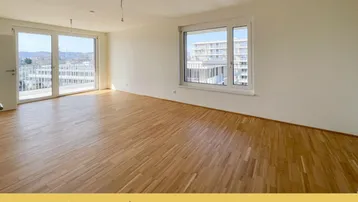 Helles Wohnzimmer mit Parkettboden und großen Fenstern, die Zugang zu einem Balkon bieten.