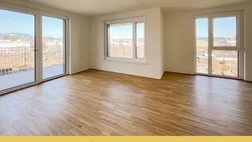 Helles, geräumiges Wohnzimmer mit Parkettboden und Zugang zu einer großen Terrasse mit Weitblick.