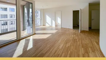 Helles Wohnzimmer mit Parkettboden, großen Fenstern und Zugang zu einem Balkon.