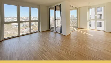 Helles, leeres Wohnzimmer mit Parkettboden und großen Fenstern, die einen weiten Stadtblick bieten.