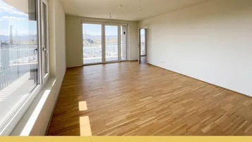 Helles Wohnzimmer mit Parkettboden, großen Fenstern und Zugang zu einem Balkon mit Aussicht.