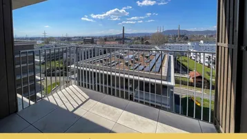 Geräumiger Balkon mit Fliesenboden und weitem Blick über die Stadt und Industrieanlagen.
