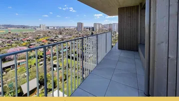 Geräumiger Balkon mit Fliesenboden und weitem Blick über Kleingärten und die Stadt.
