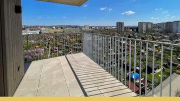 Geräumiger Balkon mit Fliesenboden und weitem Blick über die Stadt und Kleingärten.