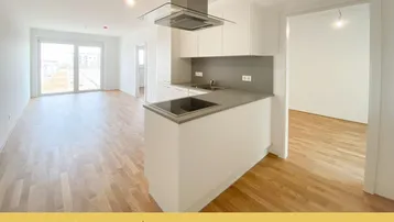 Heller offener Wohn-Essbereich mit moderner Einbauküche, Kochinsel und Zugang zum Balkon.