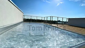 Dachterrasse mit integriertem Wasserbecken und Holzboden unter strahlend blauem Himmel.