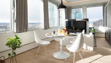 Heller Wohn- und Essbereich mit großen Fenstern, Stadtblick und modernem Esstisch.