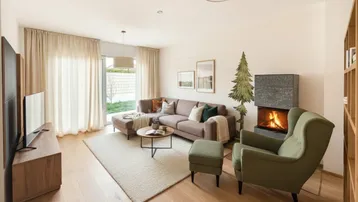 Gemütliches Wohnzimmer mit Kamin, Holzboden und Zugang zu einem Außenbereich.