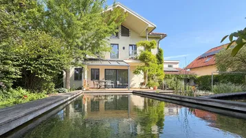 Großzügiger Gartenbereich mit Naturpool, Holzdeck und Terrasse hinter dem Haus.