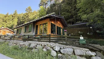 Charmantes Holzhaus im alpinen Stil, umgeben von üppigem Grün und Wald.