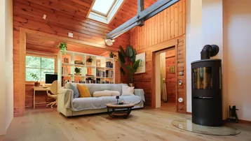 Gemütliches Wohnzimmer mit Holzwänden, Holzboden, Kaminofen und Dachfenster.