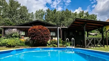 Holzhaus mit erfrischendem Pool und überdachtem Sitzbereich im grünen Garten.