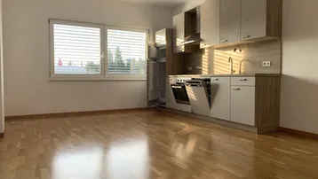 Helle, moderne Küche mit Einbaugeräten, Parkettboden und Fenster mit Jalousien.