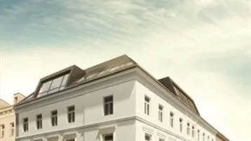 Historisches Gebäude mit klassischer Architektur und modernem Dachausbau unter einem bewölkten Himmel.