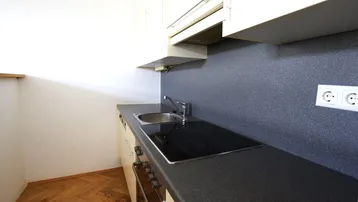 Kleine, funktionale Küche mit dunkler Arbeitsplatte und integriertem Kochfeld.