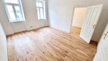 Helles, leeres Zimmer mit neuem Parkettboden und zwei Fenstern, bereit zur individuellen Gestaltung.
