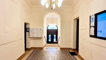 Langer, eleganter Flur mit auffälligem Schachbrettmuster-Fliesenboden und klassischem Kronleuchter.