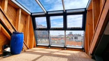 Heller Dachbodenraum im Rohbau mit großen Dachfenstern und Stadtblick, bereit für den Ausbau.
