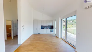 Heller offener Wohn- und Essbereich mit integrierter Küche, Holzboden und Zugang zur Terrasse.