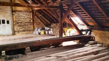 Geräumiger Rohdachboden mit sichtbaren Holzbalken und Ziegelwänden, bietet Potenzial für Ausbau.
