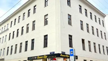 Eckgebäude mit klassischer Architektur und Gewerbefläche im Erdgeschoss in urbaner Umgebung.