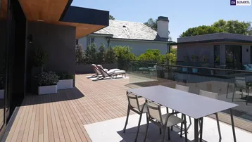 Großzügige Holzterrasse mit Essbereich und Sonnenliegen, umgeben von Glasgeländern.