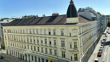 Historisches Eckgebäude mit eleganter Fassade und Mansarddach in städtischer Umgebung.
