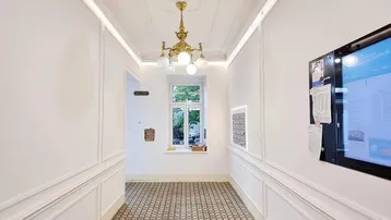 Heller Eingangsbereich mit gemustertem Fliesenboden, Stuckdecke und klassischer Deckenleuchte.