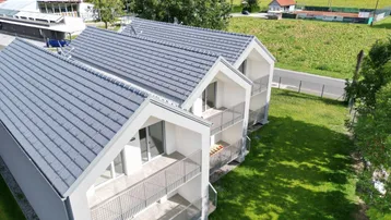 Luftaufnahme einer Reihe moderner Häuser mit Balkonen und weitem Blick auf die grüne Landschaft.