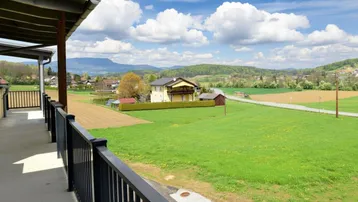 Weitläufiger Ausblick vom Balkon auf die grüne Landschaft und ferne Berge.