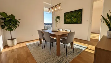 Heller Essbereich mit Holztisch, modernen Stühlen und Zugang zum Balkon, ergänzt durch eine Mooswand.