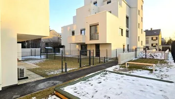 Modernes Mehrfamilienhaus mit klarer Architektur und gepflegter Außenanlage im Winter.