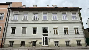 Historische Fassade eines Mehrfamilienhauses mit vielen Fenstern und klassischer Architektur.