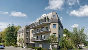 Moderne Wohnanlage mit mehreren Balkonen und Mansarddach in grüner Umgebung.