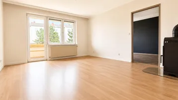 Helles Wohnzimmer mit Laminatboden, Heizkörper und Zugang zu einem Balkon.