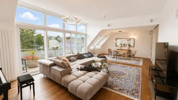 Lichtdurchfluteter Wohn-Essbereich mit großem Sofa, Holzboden und Zugang zum Balkon.