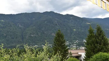 Panoramablick auf die bewaldeten Berge unter einem bewölkten Himmel, von einem Balkon aus.