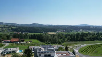 Luftaufnahme einer modernen Wohnanlage mit Photovoltaikanlagen und weitem Blick über die grüne Landschaft.