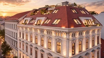 Elegantes Gebäude mit historischer Fassade und modernen Dachterrassen bei Sonnenuntergang.