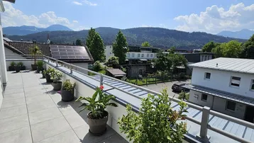 Weitläufige Dachterrasse mit vielen Pflanzen und Panoramablick auf die umliegende Berglandschaft.