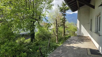 Außenterrasse mit üppigem Grün, Blick auf die Berge und viel natürlichem Licht.